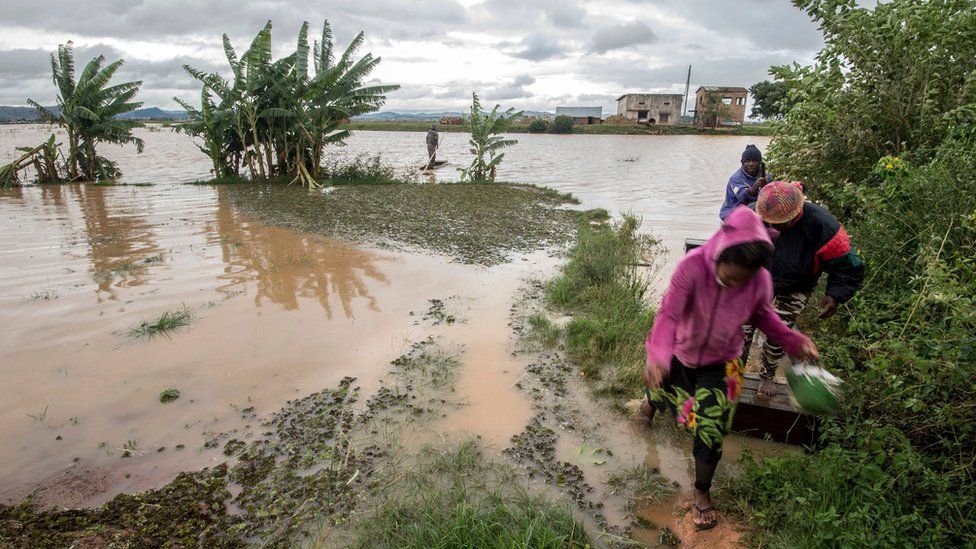 Workers take a makeshift boat to cross flooded vegetable gardens in Madagascar"s capital Antananarivo, on Thursday, March 9, 2017