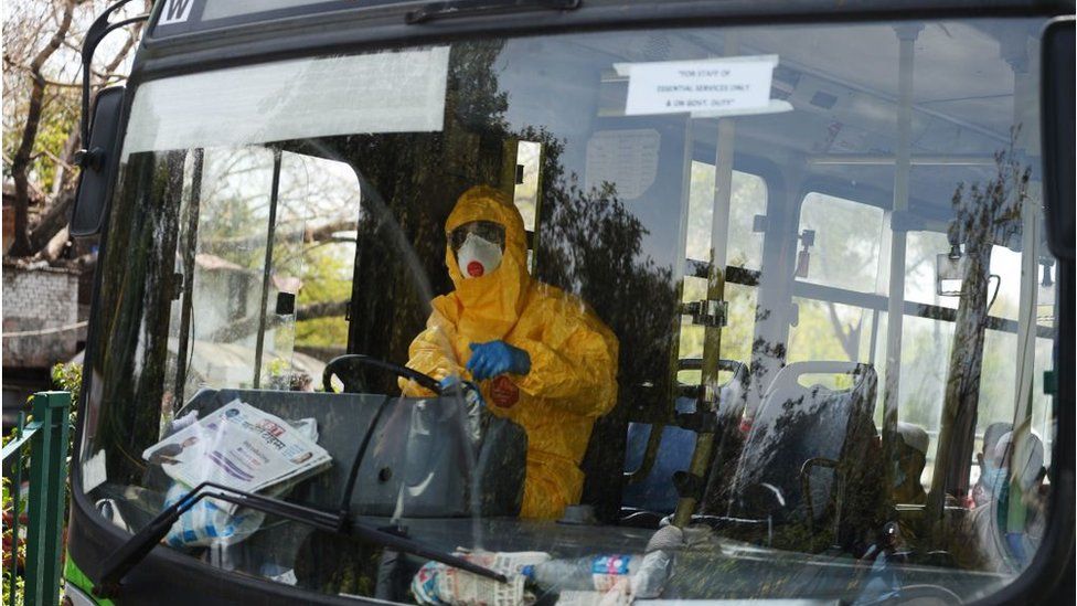 A man (in yellow) dressed in protective gear drives a special service bus taking people to a quarantine facility amid concerns about the spread of the COVID-19 coronavirus in Nizamuddin area of New Delhi on March 31, 2020
