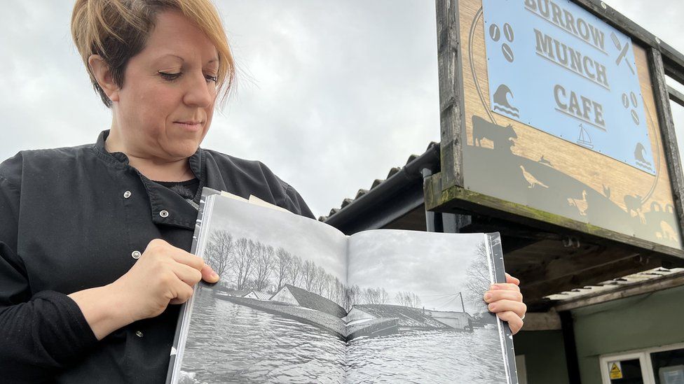 Women stood and holding a book showing flooded building