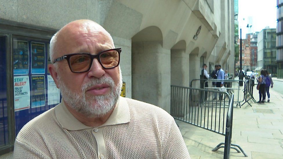 Joe Collett, a man with grey hair and glasses, wearing a brown polo shirt, speaking outside the Old Bailey.