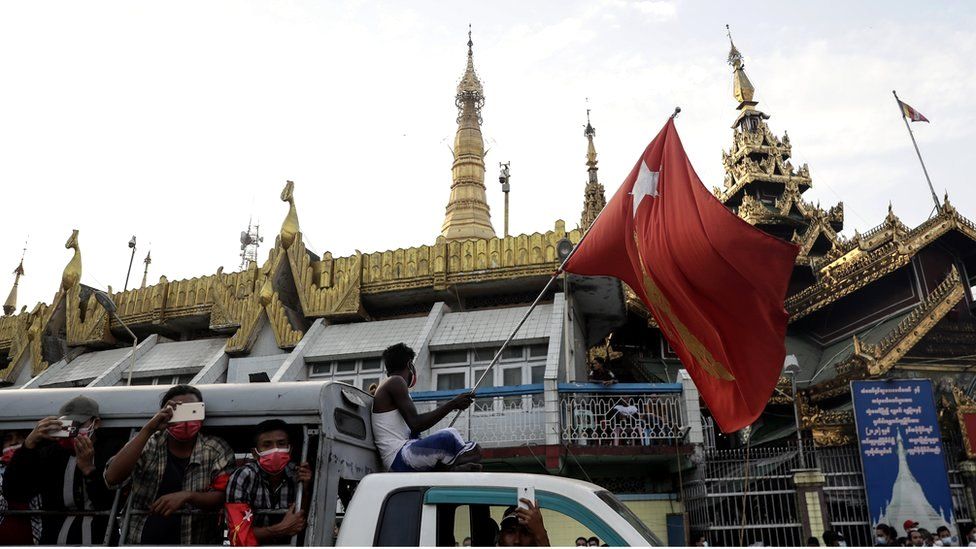 A demonstrator waves a flag of the National League for Democracy (NLD) party, led by detained Myanmar State Counsellor Aung San Suu Kyi