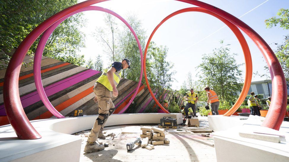 Workmen in fluorescent jackets preparing a colourful and spherical-shaped sculpture for the show