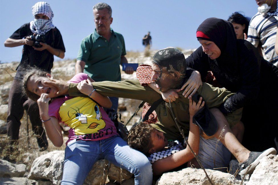 Palestinians try to prevent an Israeli soldier from detaining a boy during a protest against Jewish settlements in the West Bank village of Nabi Saleh, near Ramallah 28 August 2015