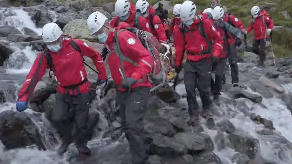 Rescuers carry Daisy across a waterfall