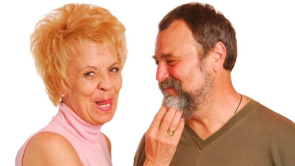 A woman touches a man's beard