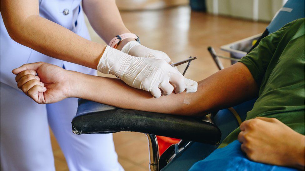 A nurse helps a man give blood