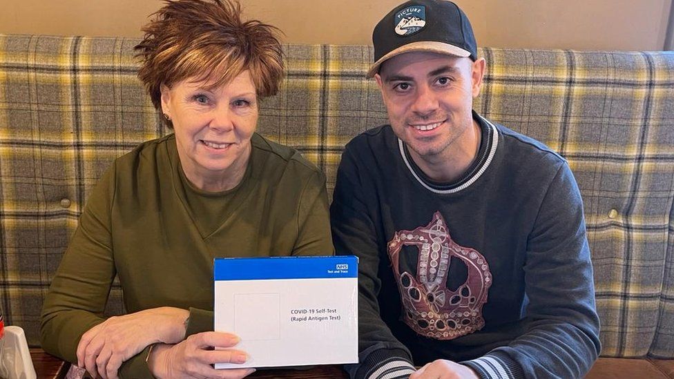 Karen and Rich Gilbert holding a box of lateral flow tests