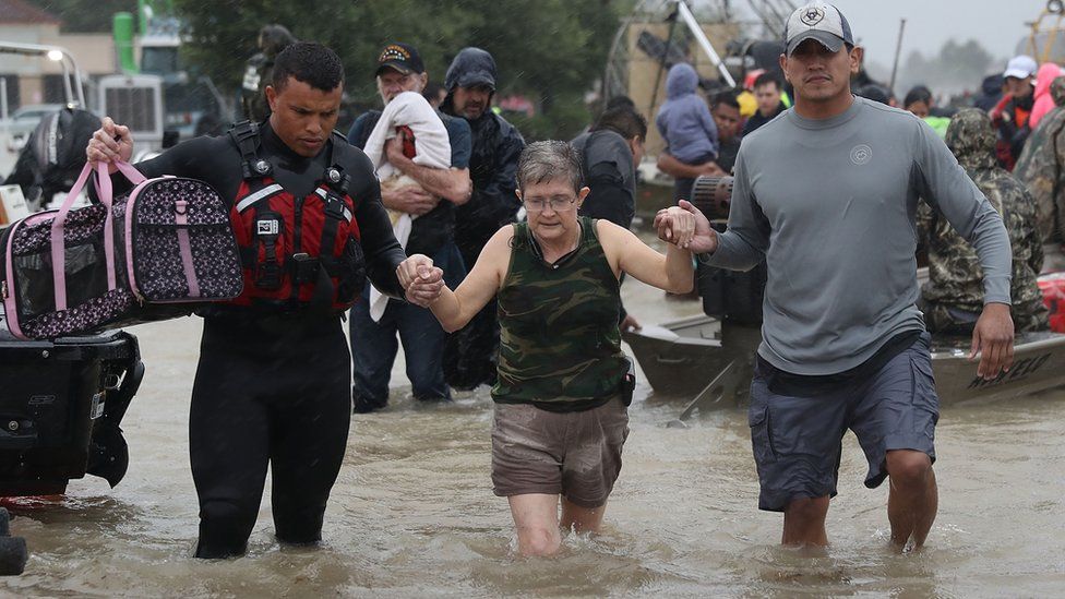 An evacuee is helped to dry land after her home was inundated with flooding from Hurricane Harvey on August 28, 2017 in Houston, Texas.