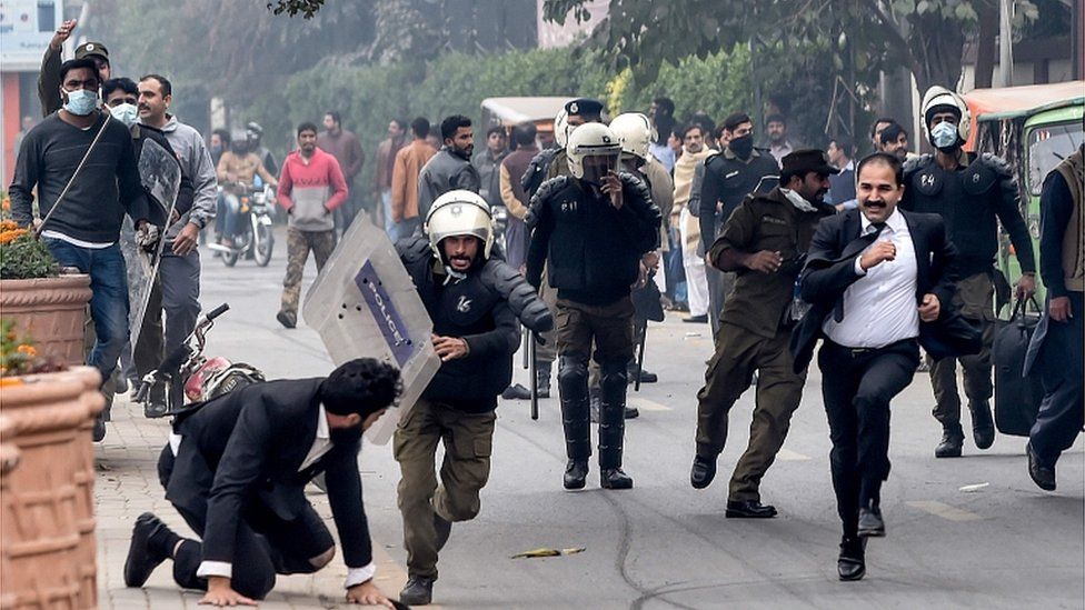 Police chase lawyers following a clash between lawyers and doctors in Lahore on December 11, 2019