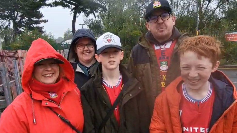 The Collins family stood outside in the rain with their Wrexham shirts on