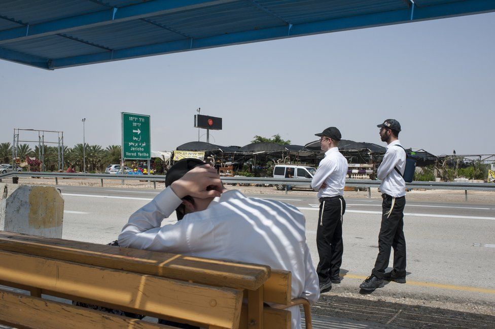 Hitchhikers standing by a road in the West Bank