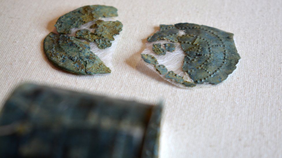 A green coloured brooch broken in half