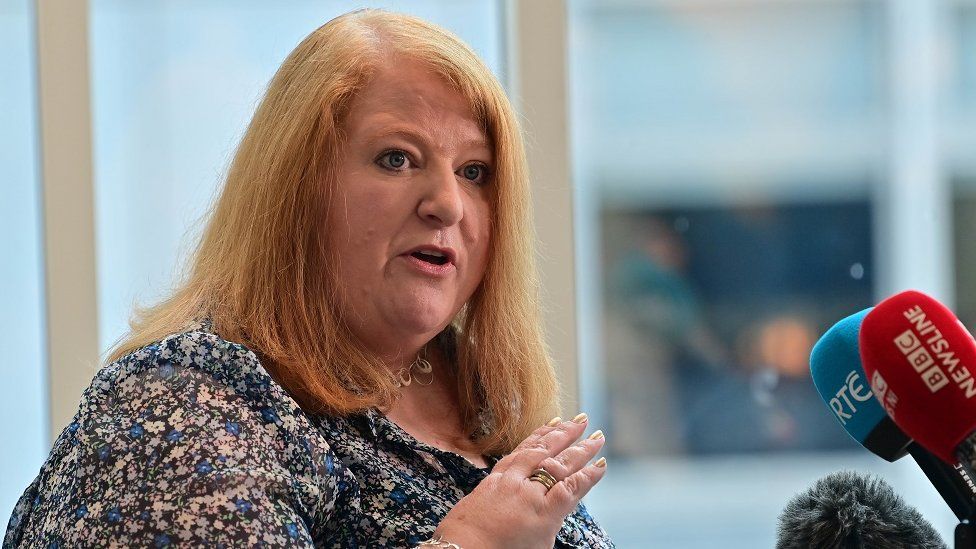 Naomi Long speaks into a red BBC Newsline microphone