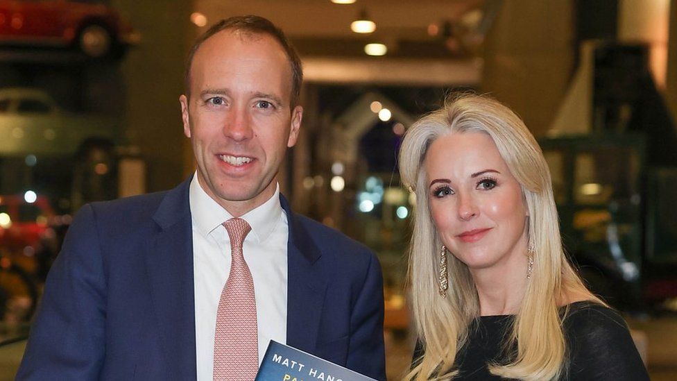 Matt Hancock and Isabel Oakeshott standing together, both smiling at the camera and holding a copy of Mr Hancock's book between them