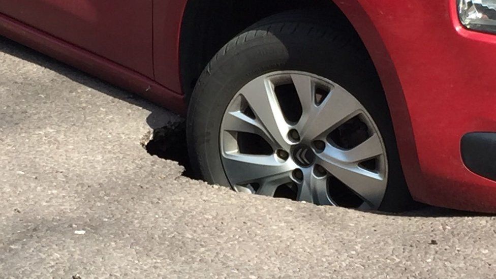 Car wheel stuck in "sinkhole"