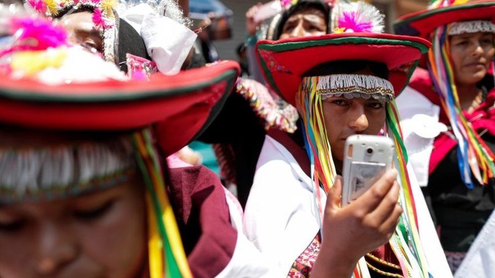 An indigenous Bolivian holds a cell phone and looks on as former Bolivian President Evo Morales returns to his home country from exile in Argentina, at the border town of Villazon, Bolivia, November 9, 2020.