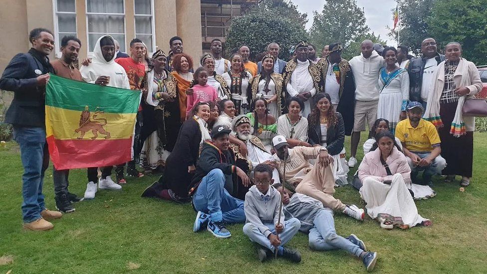 A group photo of people holding up the Rastafari flag