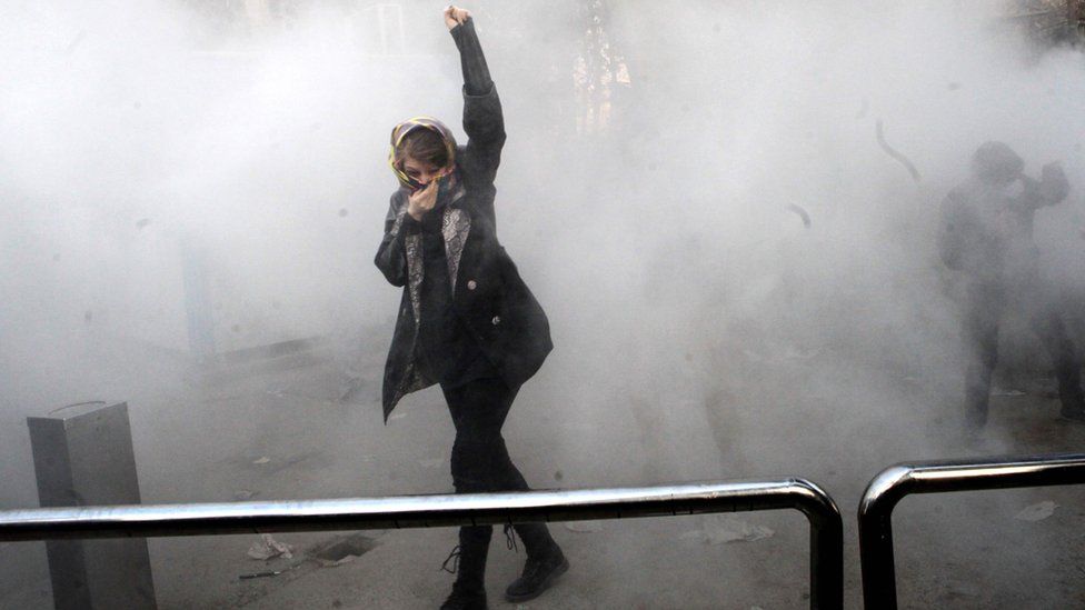 An Iranian woman raises her fist amid the smoke of tear gas
