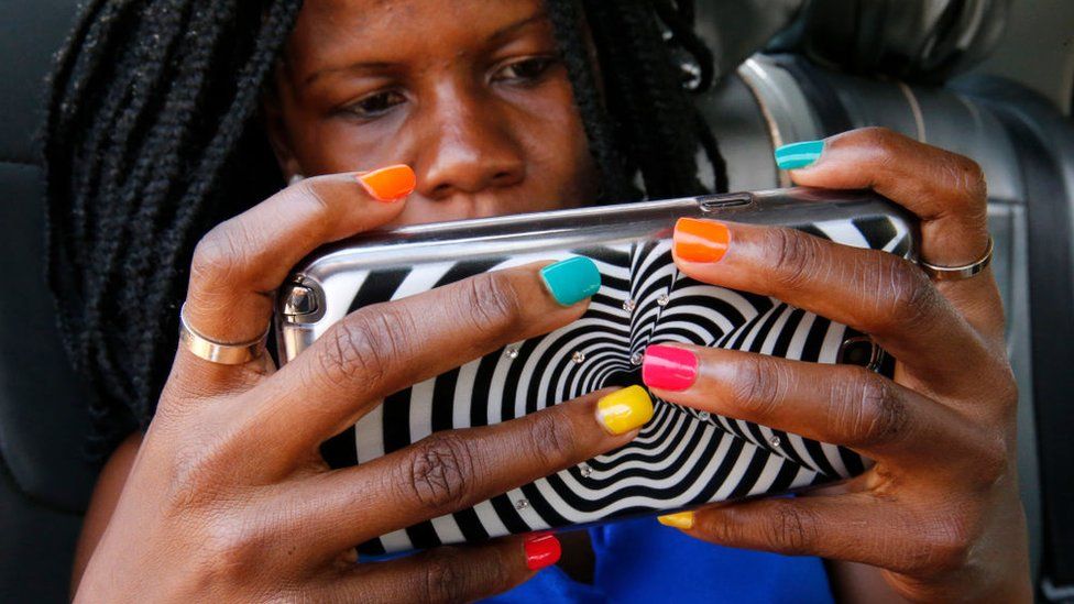 Ugandan woman with painted nails using a cell phone.
