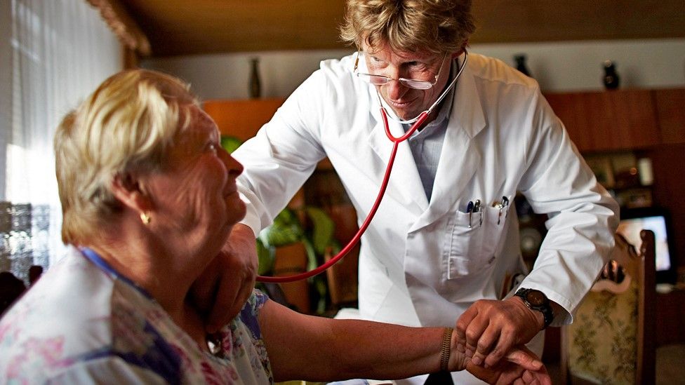 Сельский врач Дитер Бэрманн измеряет кровяное давление пациентке Гизеле Херферт в доме пациентки в Заксендорфе, Германия.