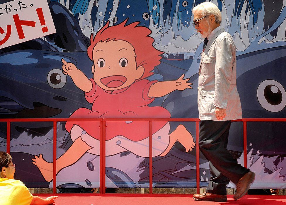 Oscar-winning Japanese animator and film director Hayao Miyazaki walks past a advertising board for a photo session following the release of his new animated movie 'Ponyo on the Cliff by the Sea' at a theater in Tokyo on 19 July 2008.