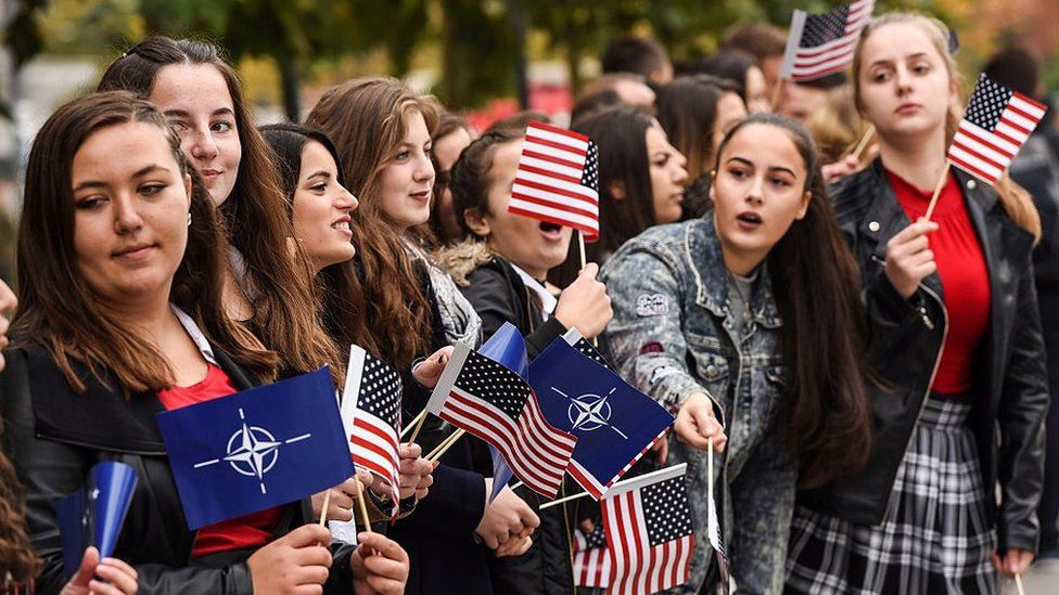Kosovo Albanian youth wave US and NATO flags during a US Army and Kosovo Security Force running competition in Pristina on 20 October 2016.