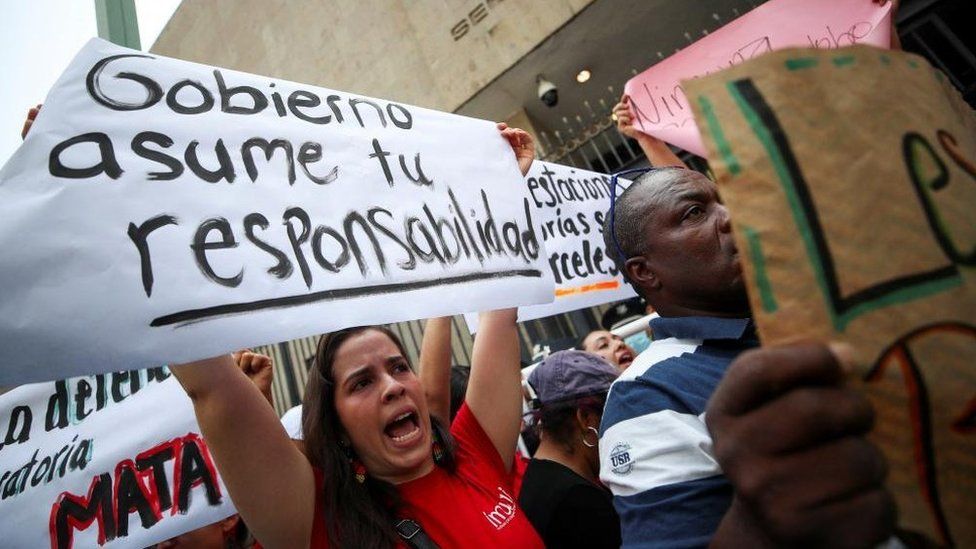 Demonstrators hold posters as they take part in a protest following the death of several migrants