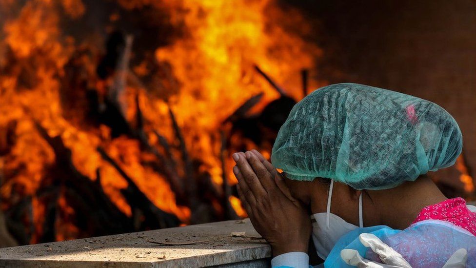 Mujer rezando cerca de pira funeraria