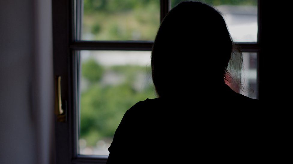 Woman in silhouette watching out of a in window