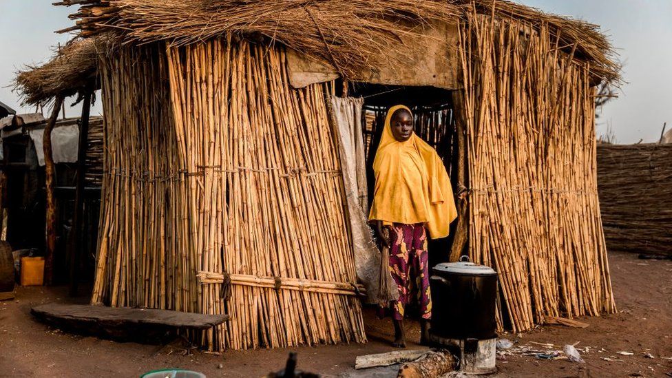 Woman standing in front of a thatched hut