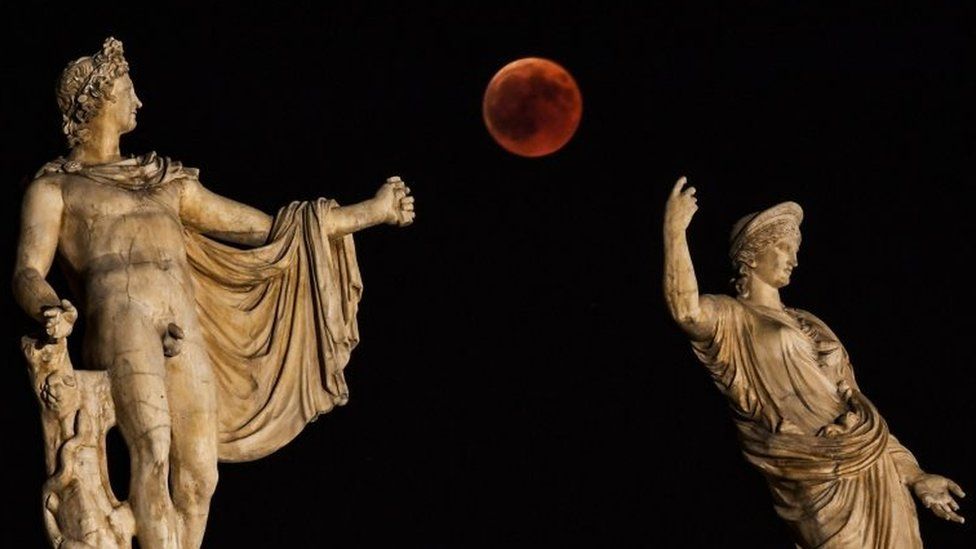 The blood moon beside a statue of ancient Greek goddess Hera and god Apollo in Athens