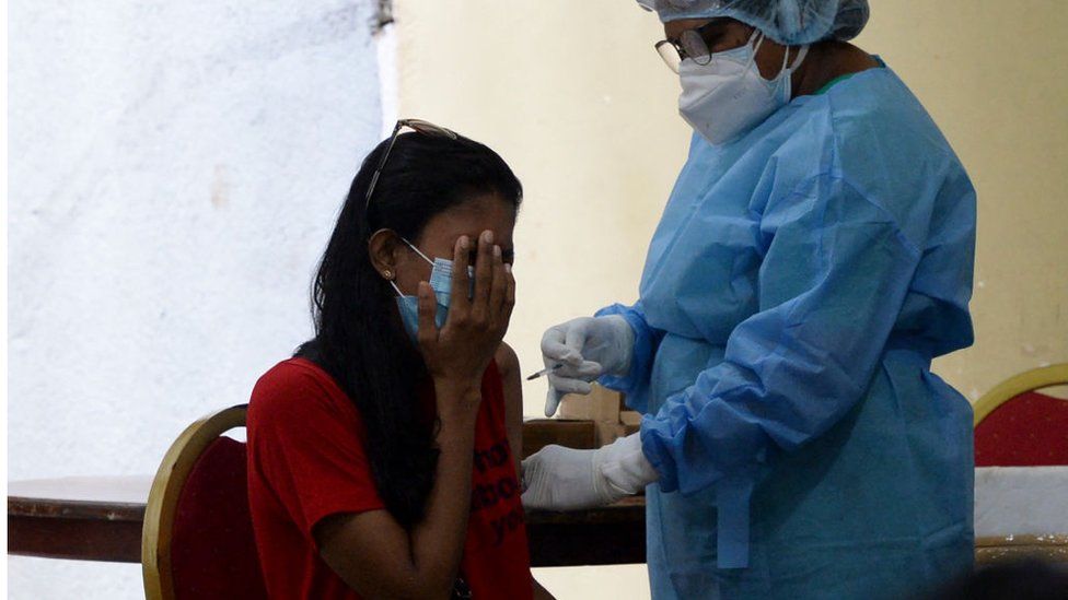 A health worker inoculates a woman with a dose of the Chinese-made Sinopharm Covid-19 coronavirus vaccine as government imposed travel restrictions and weekend lockdown to curb the spread of Covid-19 coronavirus in Colombo