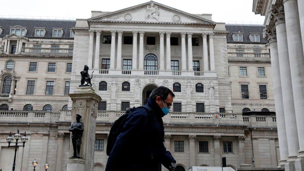 A man wearing protective face mask walks past the Bank of England in the City of London