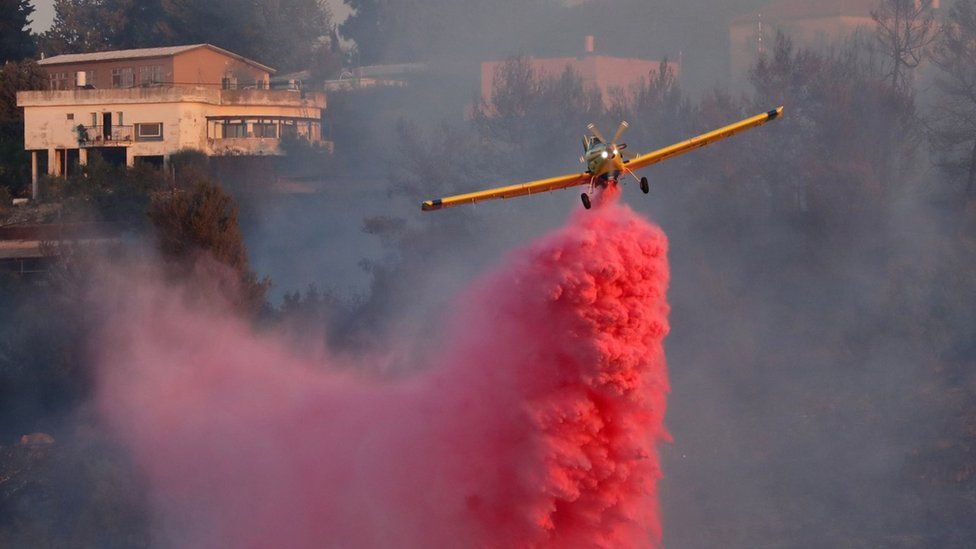 An Israeli fire-fighting plane drops flame retardant at the village of Givat Yearim, near Jerusalem on 16 August 2021