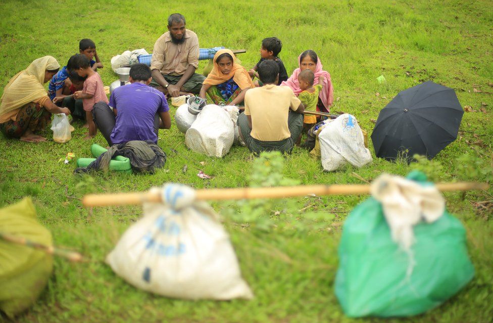 A Rohingya family sit in a field for a much-needed meal