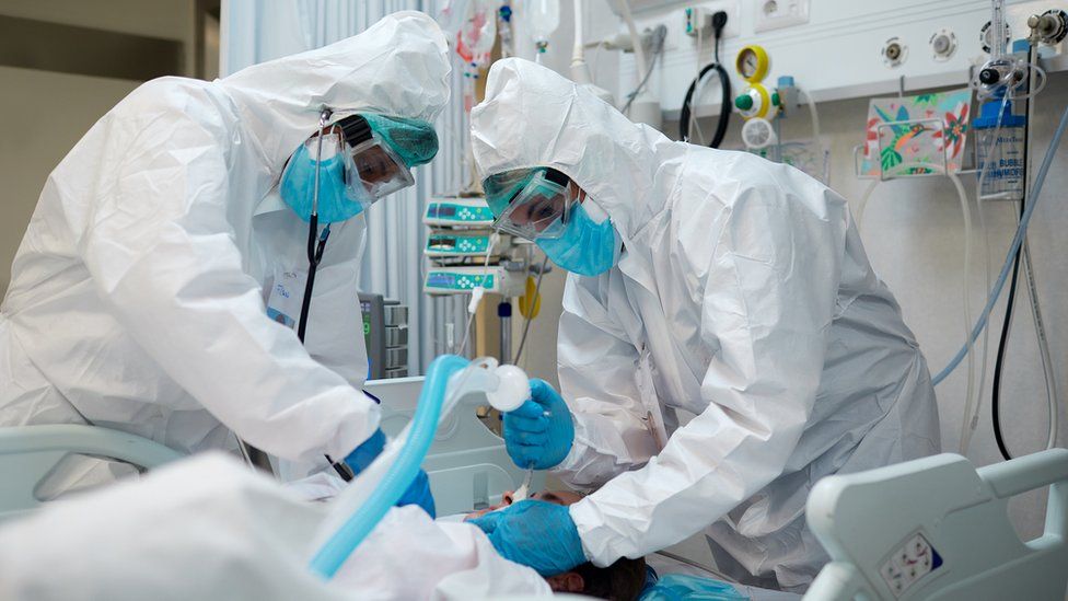 doctors in hazmat suits and masks treat patient