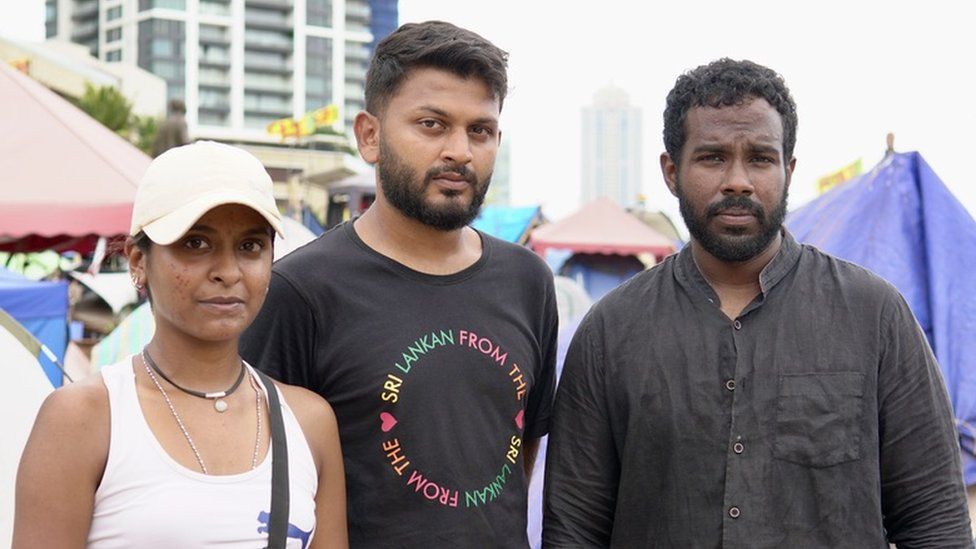 Three young people standing in protest camp