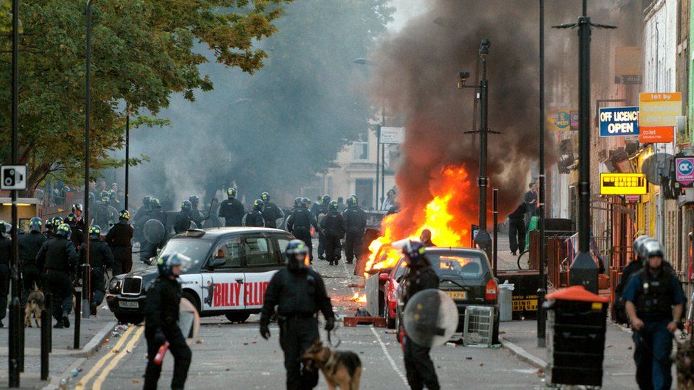 Riot police look on as a car burns