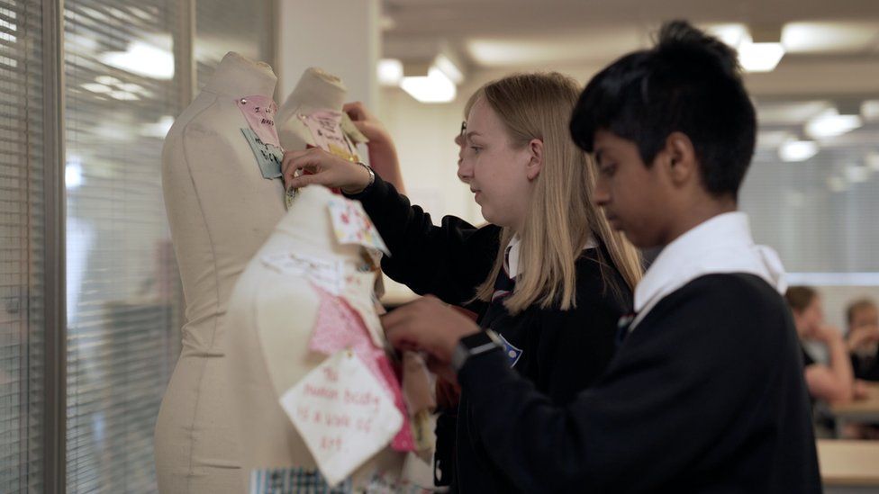 Children pinning material on a mannequin