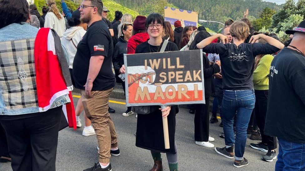 A protester holds a sign as she takes part in a march led by New Zealand political party Te Pati Maori