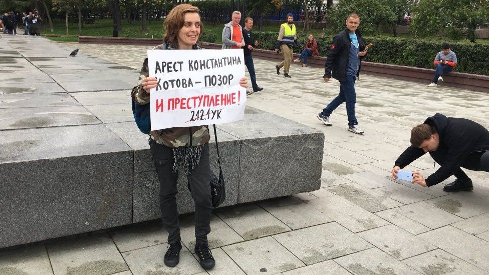 A protester holds a placard decrying an arrest as a disgrace on 17 August 2019
