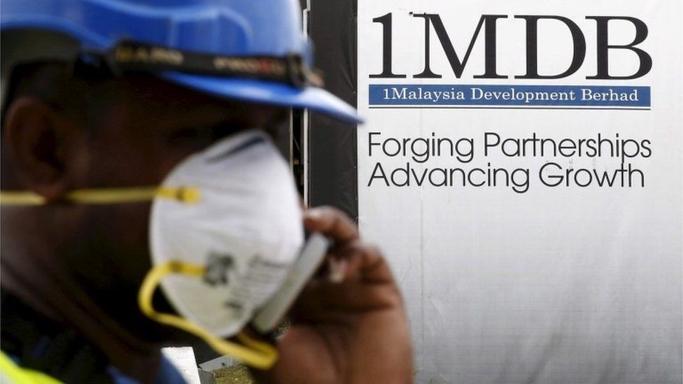 A construction worker walks past a 1MDB sign in KL, Malaysia