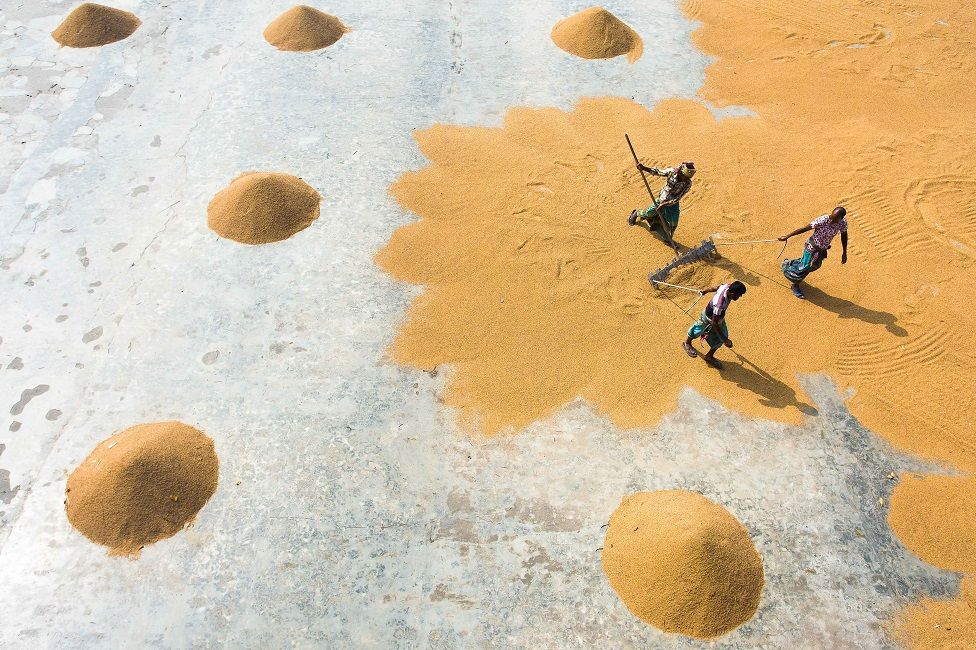 An aerial shot showing people sweeping up grain from the floor