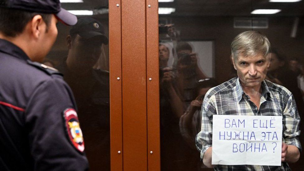 Moscow city deputy Alexei Gorinov, stands with a poster reading ""Do you still need this war?" i