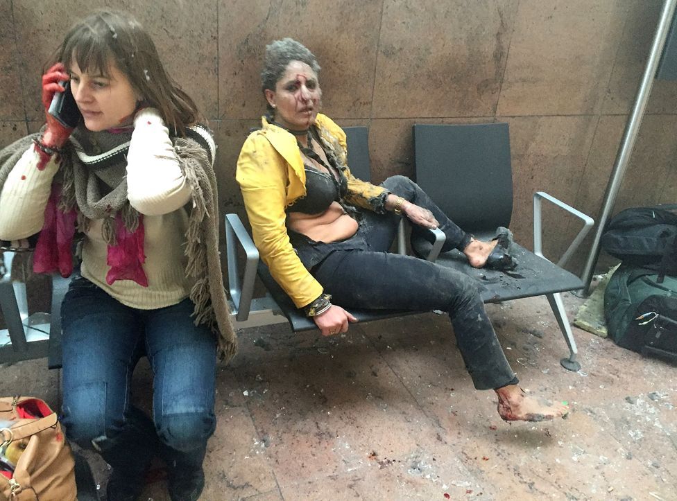 Dos mujeres cubiertas de polvo, una de ellas con el rostro ensangrentado, tras las explosiones en el aeropuerto de Bruselas