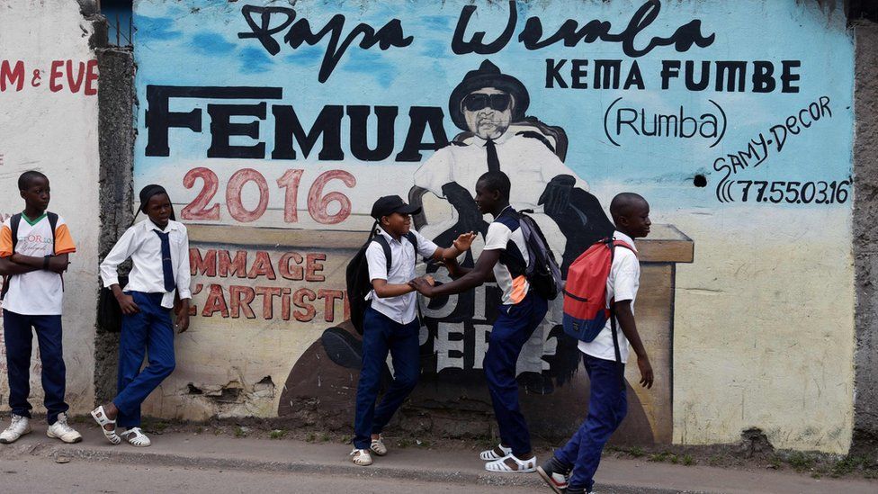 Youngsters stand next to a mural in tribute to Congolese rumba star Papa Wemba at Anoumabo district of Abidjan, Ivory Coast - Monday 20 February 2017