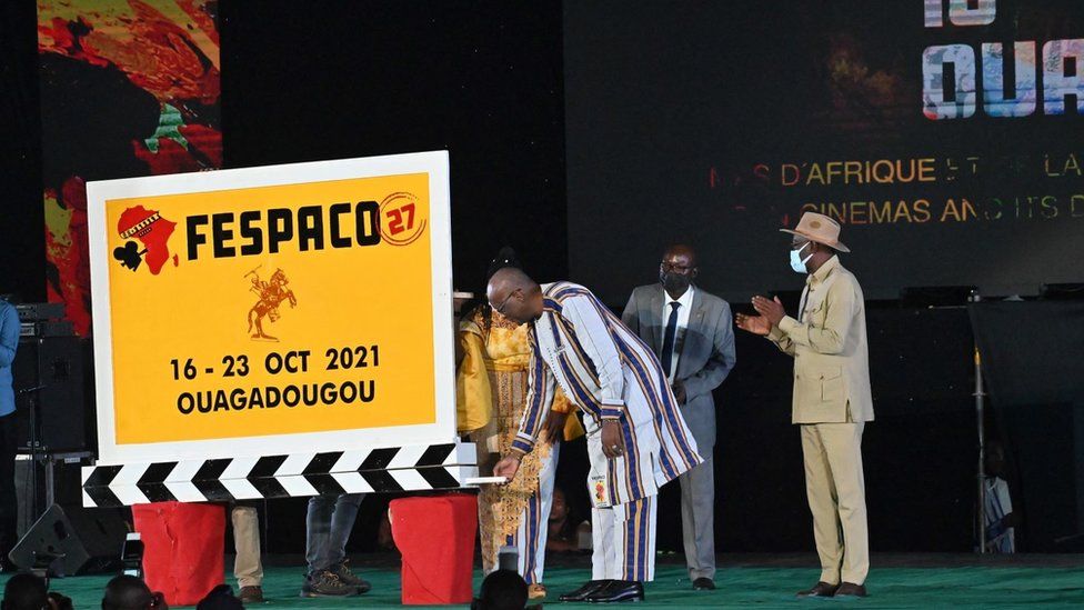 Burkina Faso's president standing next to a big sign which says: Fespaco 16 - 23 October 2021
