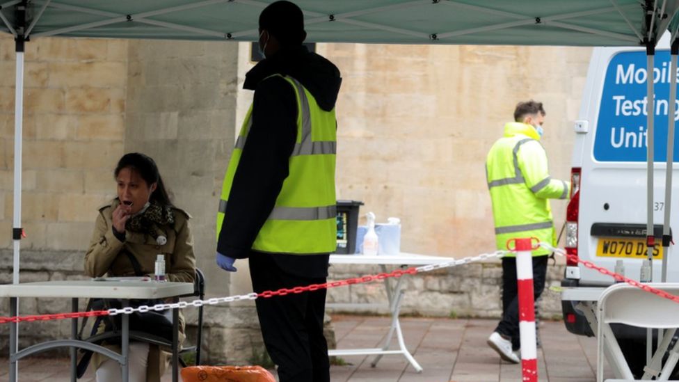 Woman takes a swab for a covid test at a mobile site in London