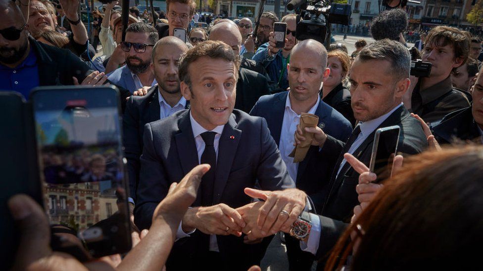 French President Emmanuel Macron meets and shakes hands with local residents of Saint-Denis on 21 April