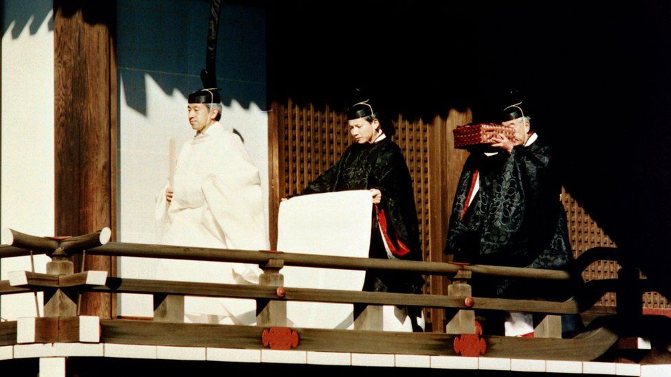 Emperor Akihito accompanied by Shinto priests carrying an Imperial Treasure at the palace (1990)